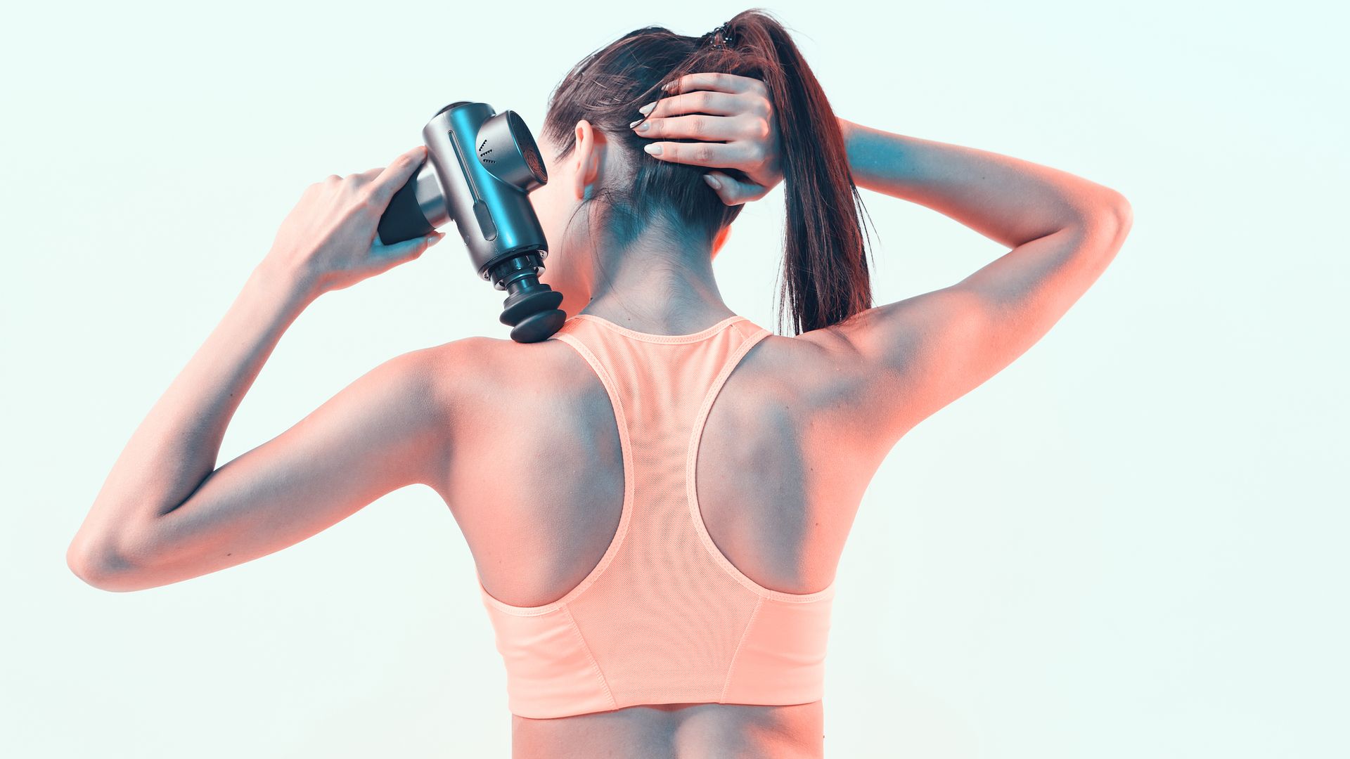 Woman using a massage gun on her shoulder.
